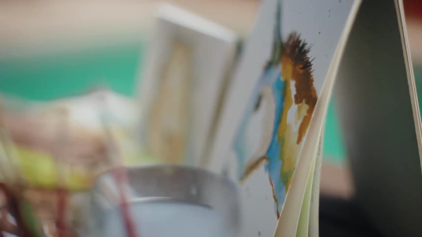 Close-up dolly shot of various paintbrushes in jars at an outdoor art station