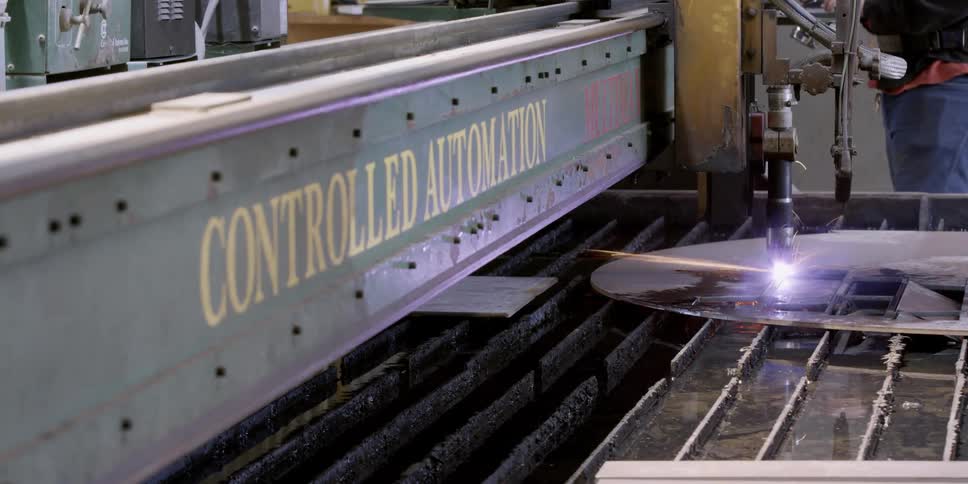 An automated tool cuts a piece of metal in a factory