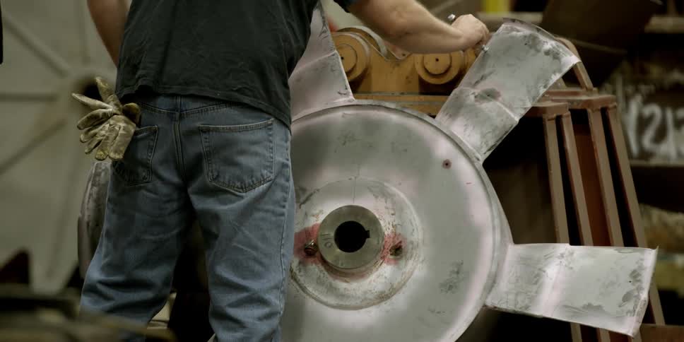 A man marks a piece of metal with a marker in a factory