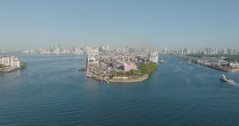 Slow aerial approach to the bustling Port of Miami, with massive cranes and a city skyline on a clear day