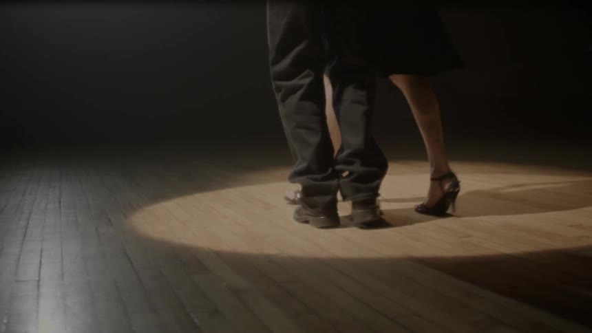 A man and woman dance on a wood floor