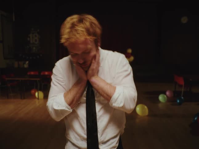 A stressed young man experiences an anxious episode, shaking his head while holding his face after a party in an empty hall