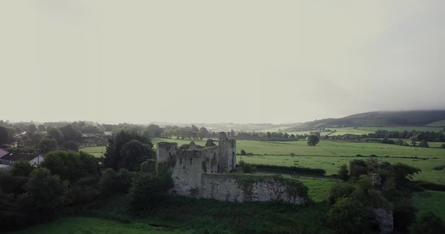 An overgrown castle on a grassy hill