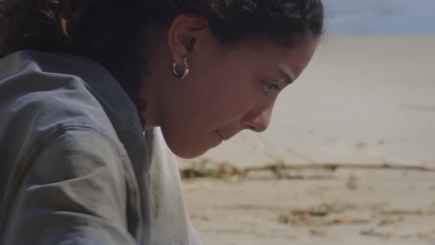 Close-up side profile of a thoughtful young woman concentrating on a task at the beach