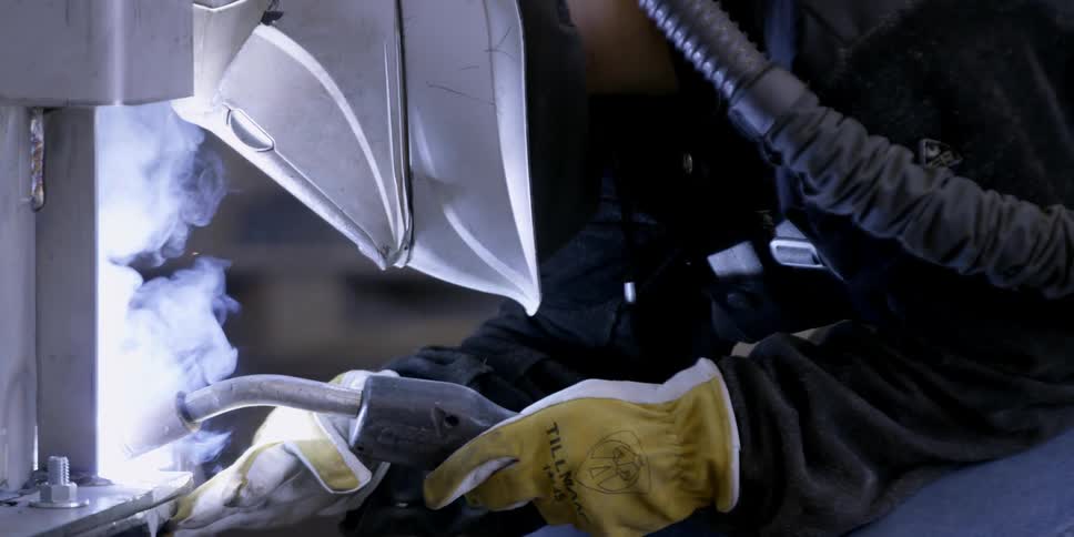 Sparks and smoke fly around a welder's mask