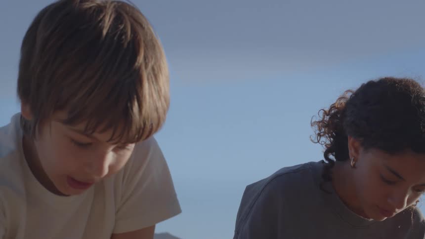 A close-up shot of a young boy and girl focused and working together on a sunny day