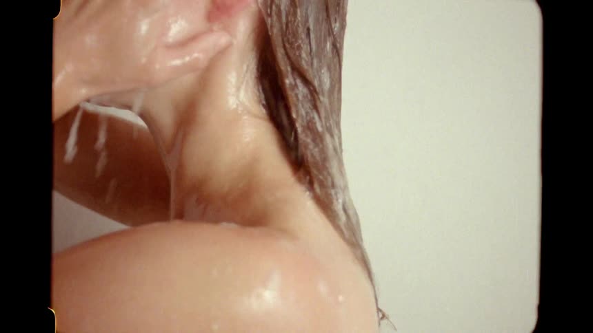 Vintage 8mm film captures an intimate close-up of a woman washing her long, wet hair in the shower