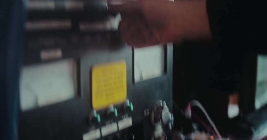 A close-up of an operator's hands adjusting the knobs and switches on an industrial machinery control panel