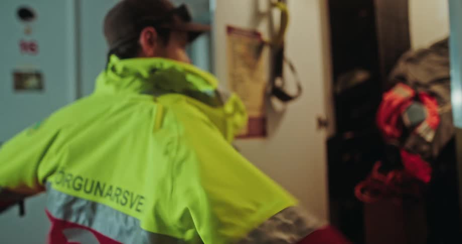 A male Icelandic search and rescue worker gets his uniform and backpack from his locker