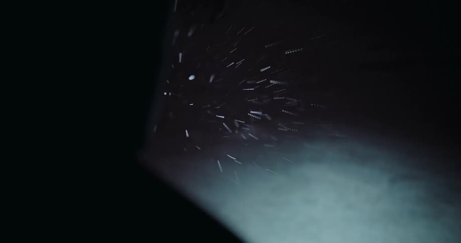 A cinematic over-the-shoulder view of a mysterious hooded figure watching a heavy snowstorm blow through the darkness at night