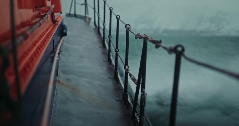 A search and rescue boat speeds through the choppy arctic waters on a cold, overcast day