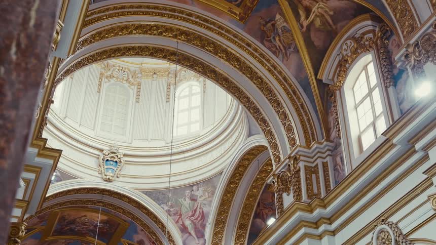 Looking up at the majestic, sunlit dome and ornate golden architecture inside a grand historical church