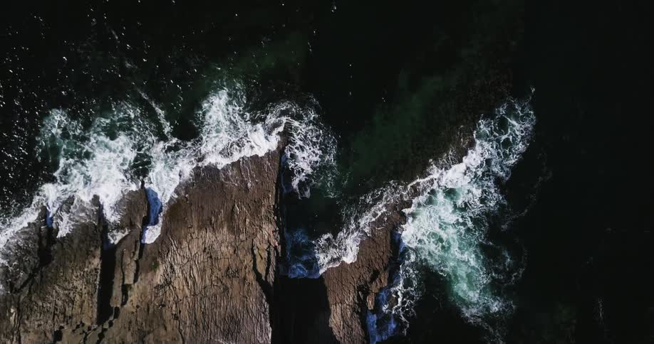 Ocean waves crash against a rocky cliff