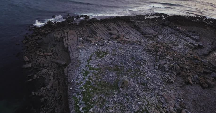 The rocky shore has heavy waves hitting the side