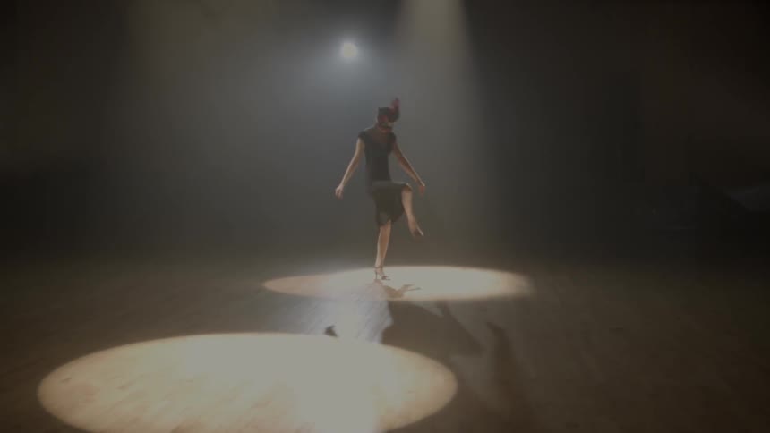 A woman is dancing under a spot light