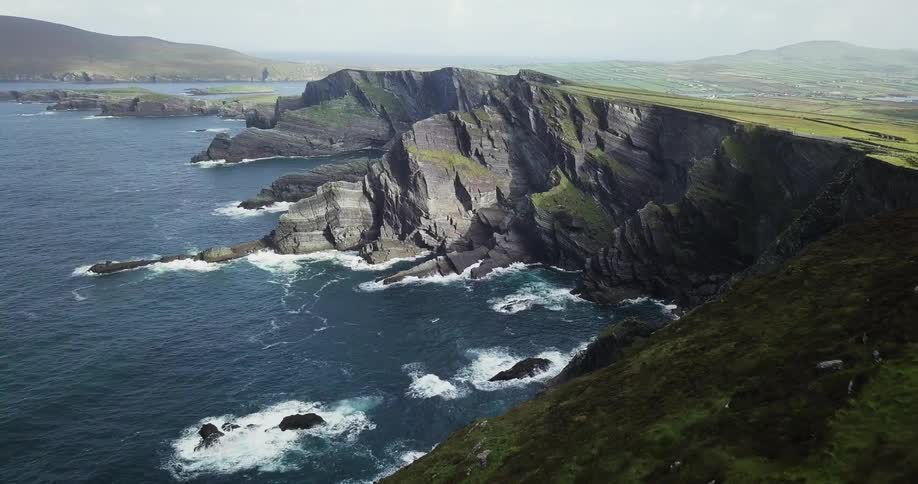 The tall cliff has waves crashing below