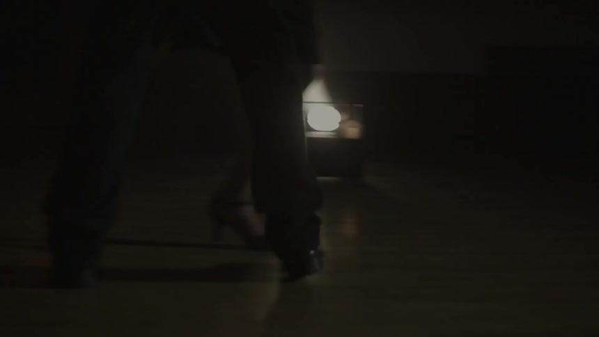 Man and woman tango dancing on a dimly lit stage