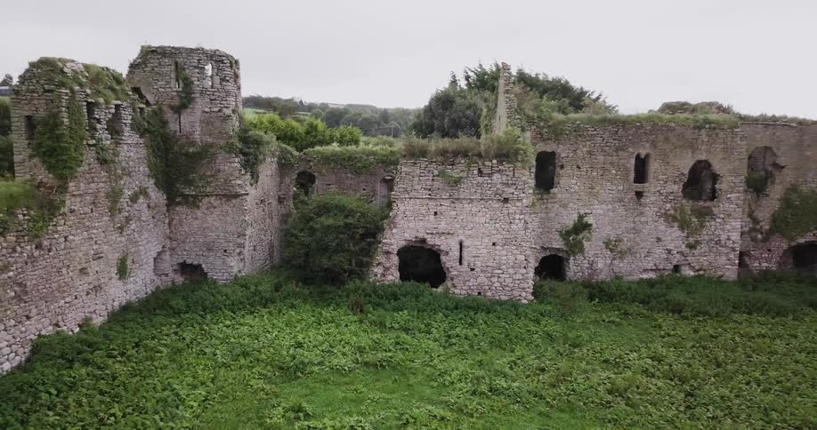 Zooming out from the remains of an old stone castle overgrown with lush greenery
