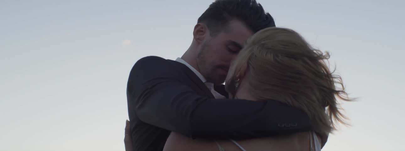 A man and woman embrace on a windy day