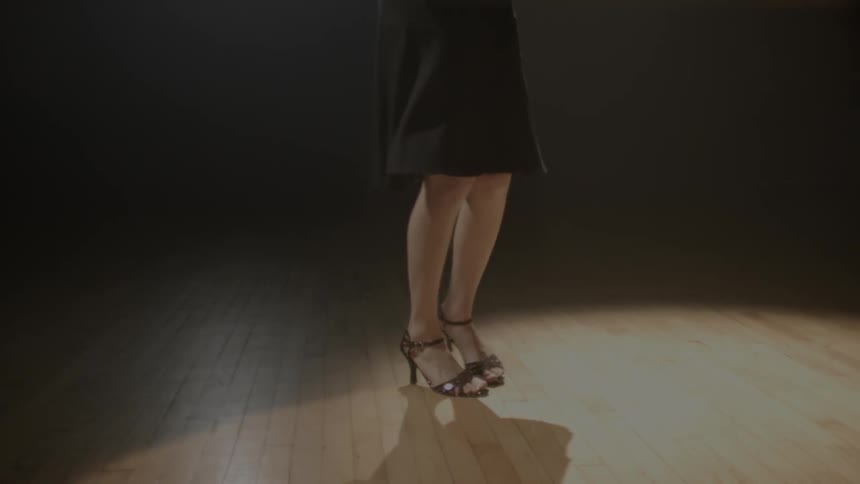 A woman dances on a wood floor