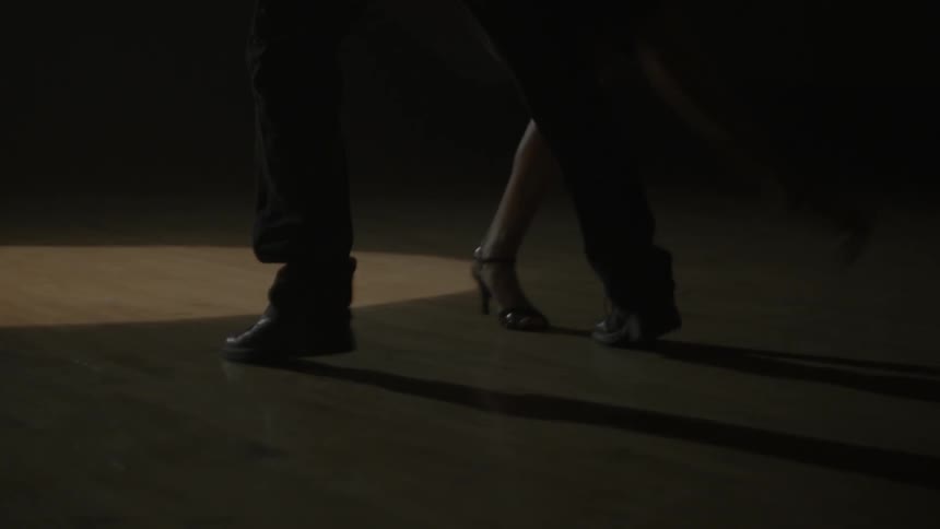 A man and woman dance on a wood floor