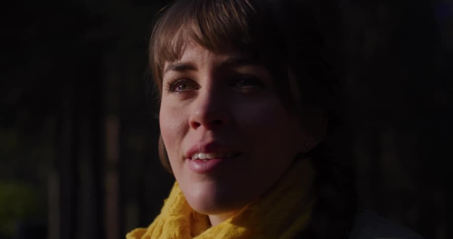 A woman's face is illuminated by golden hour light as her expression softens from worry to a peaceful smile