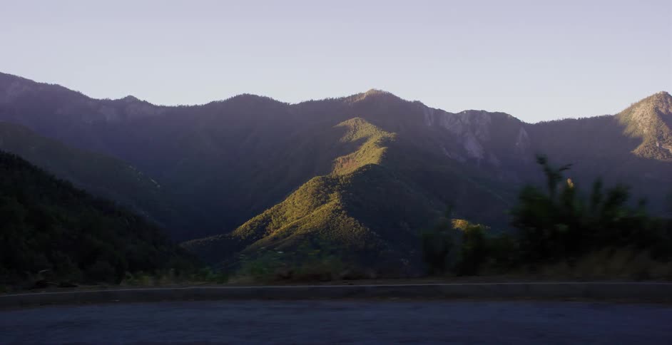 A slow-motion tracking shot past a stunning mountain range illuminated by the golden hour sun