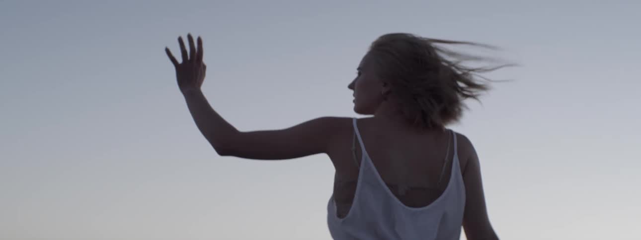 A woman lifts her arm to the blowing wind