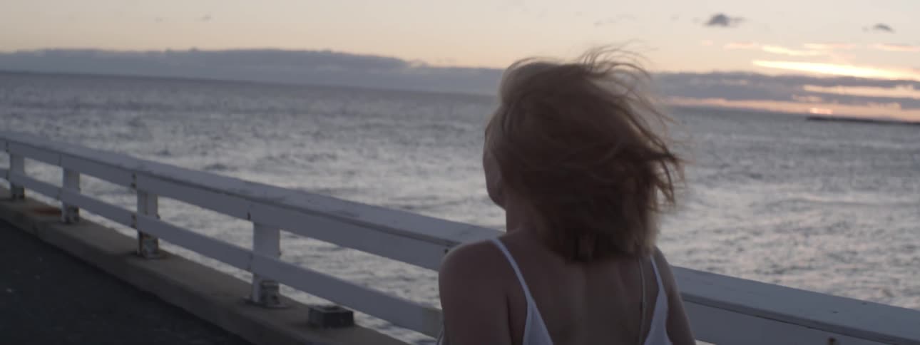A woman walks on a pier on a windy day