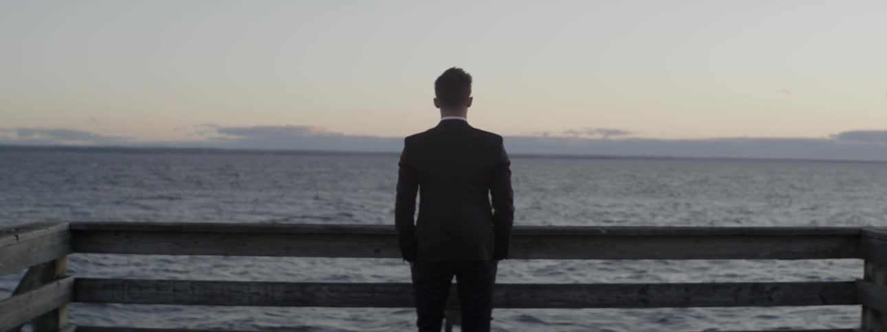 A man in a suit watches the water