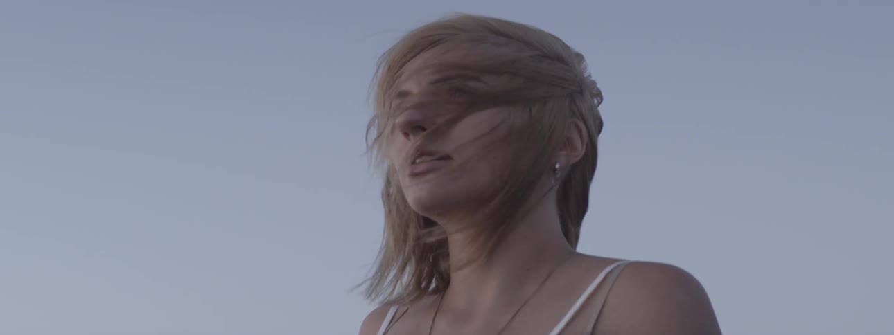 A woman stands outside as the wind blows her hair