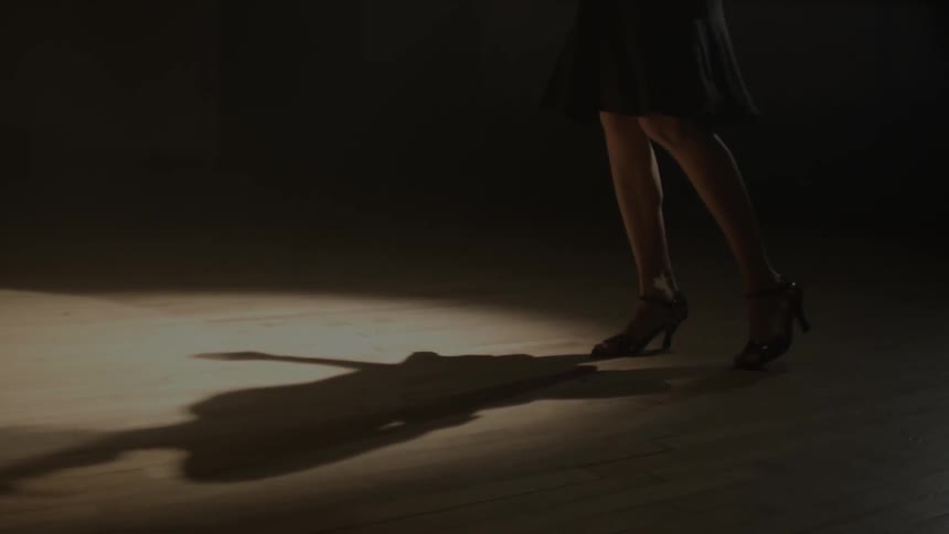 A woman in heels dances on a wood floor