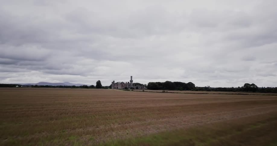 Fields of grass lead up to a mansion