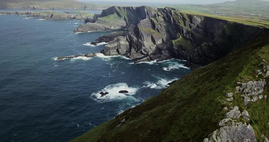 The waves crash against the cliff lined shore