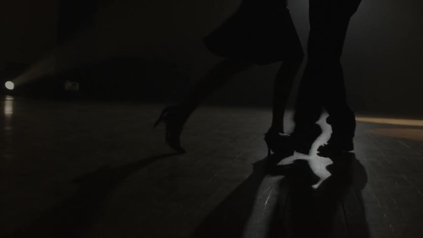Two people dance slowly under a spotlight