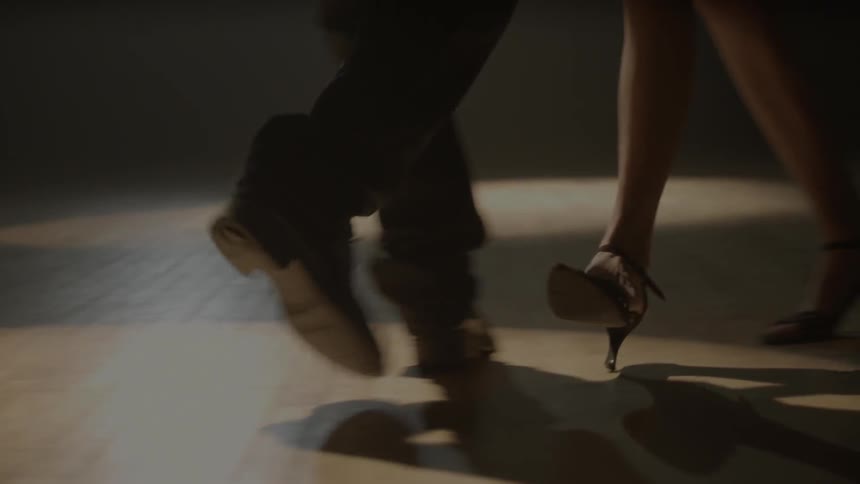 A man and woman dance on a wood floor