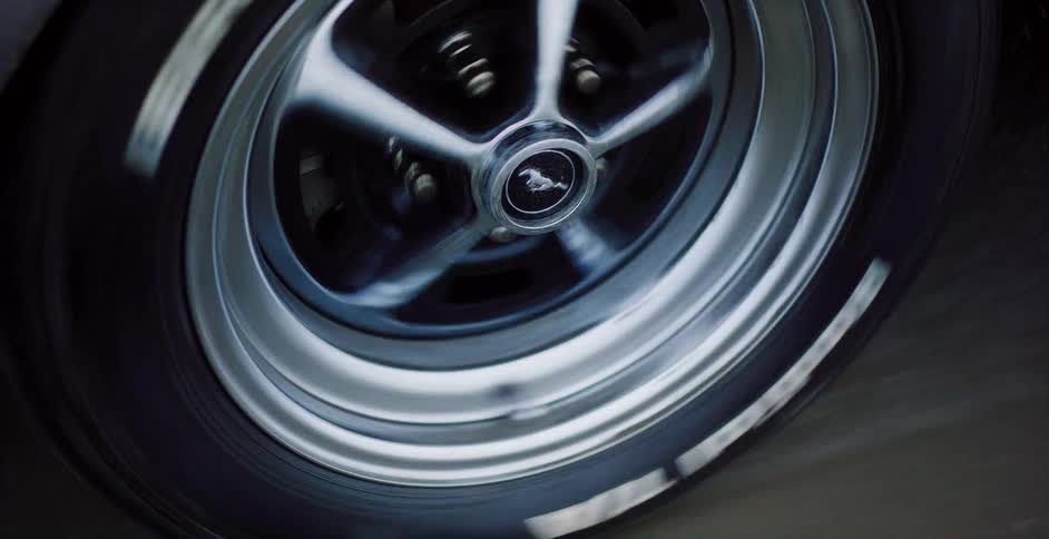 A close-up shot of a classic Ford Mustang muscle car's wheel spinning at high speed