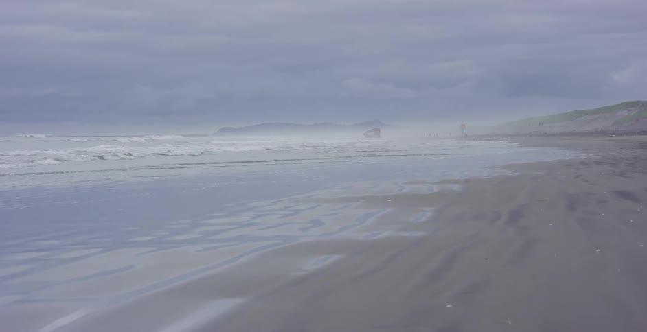 A calm, foggy morning on the coast as the tide gently recedes from the wet sand