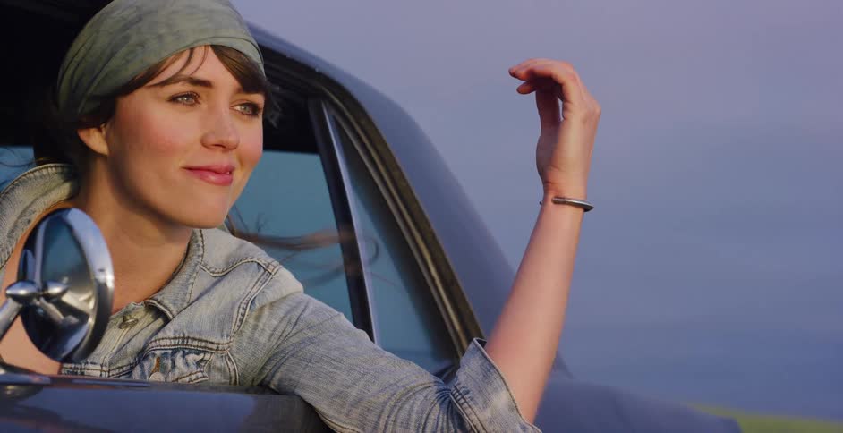 Cinemagraph of a happy young woman enjoying the breeze as she looks out a car window, her hair blowing in the wind