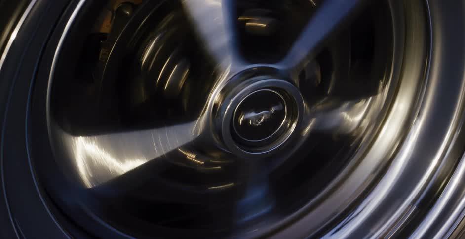 Close up of a classic muscle car's chrome wheel spinning fast, creating a motion blur effect