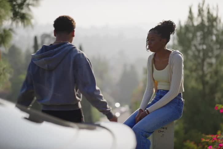 A stylish young Black couple enjoys a relaxed conversation at a scenic overlook on a hazy day