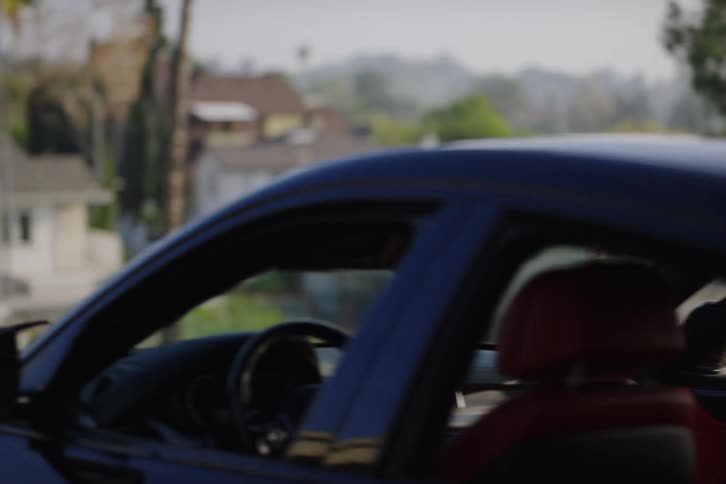 A young Black man says goodbye to his friend and gets into his car in slow motion after a conversation at a scenic overlook