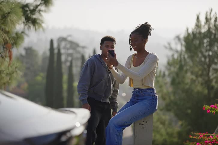 Happy teenage friends laugh and take silly photos together with a smartphone on a hillside road