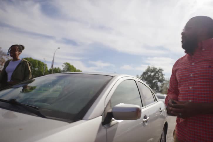 A proud father exits his car in slow motion and happily gives the keys to his excited teenage daughter