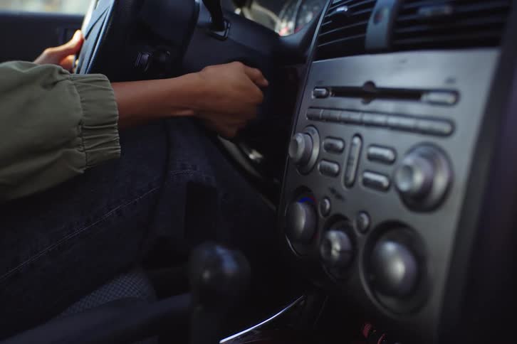 Close up of a woman's hands inserting a key to start the car engine and adjusting the climate control before driving