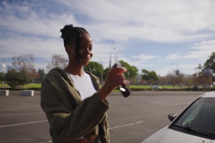 Excited father surprises his happy teenage daughter by gifting her a car in a sunny parking lot