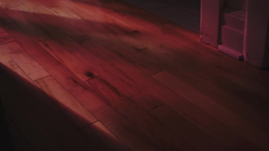 A dramatic time-lapse of sunlight shifting and changing color from white to red on a hardwood floor