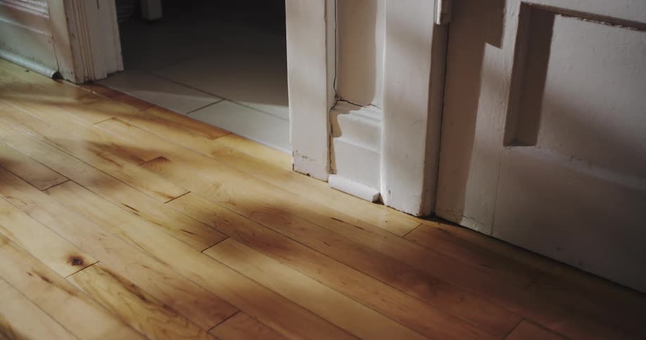 Time-lapse of sunlight shifting to a menacing red emergency light on an old hardwood floor