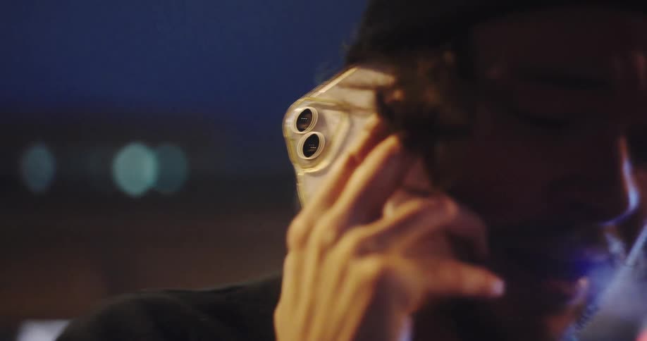 Slow-motion close-up of a troubled young man on the phone at night, looking sad and worried