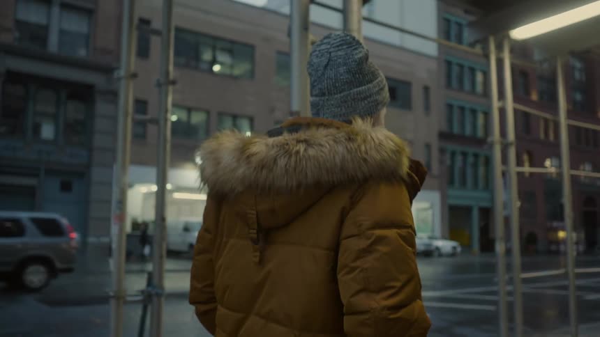 A man in a large coat walks down a city street